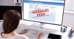 woman looking at online banking with 'overdraft fees' on screen