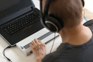 Man using braille keyboard on computer.