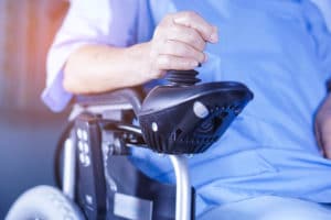 person in a wheel chair using a joystick assistive device