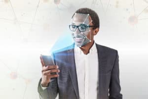 Smiling African American businessman in glasses using smartphone with face recognition technology over white background with polygons. Toned image double exposure