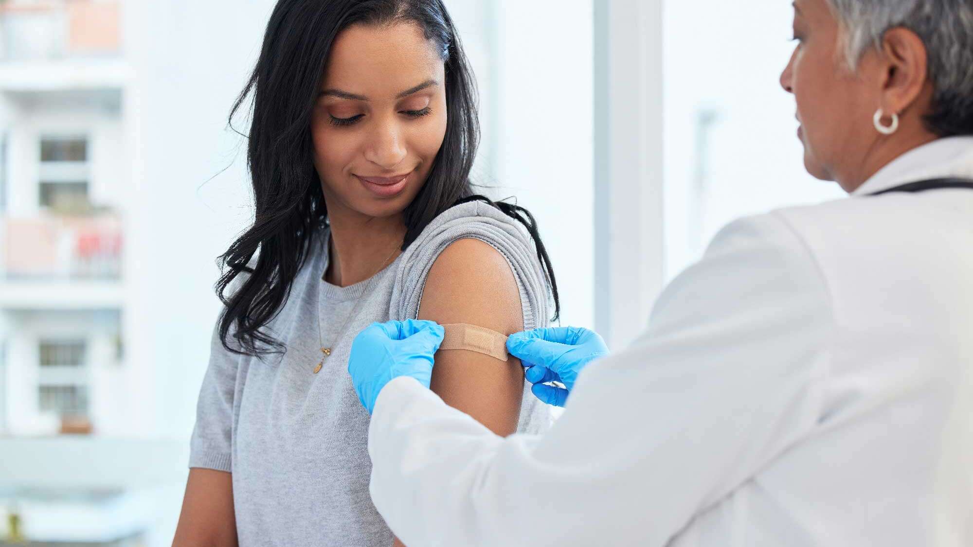 doctor placing a bandage on a woman's arm over a shot