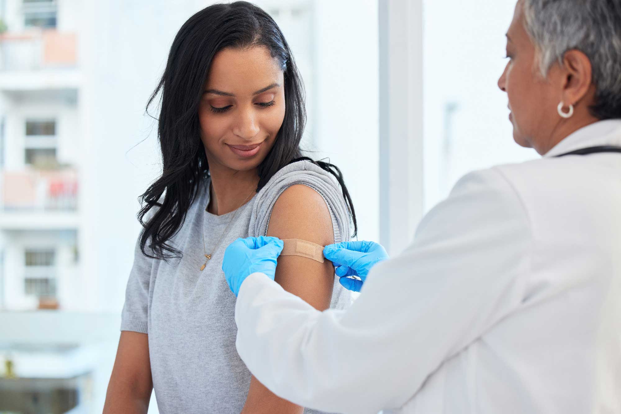 doctor placing a bandage on a woman's arm over a shot